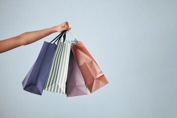 Hands, shopping bags and purchase on studio mockup for fashion, discount or sale against a gray...