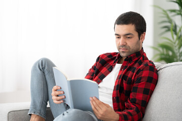 Hispanic man reading a book indoors