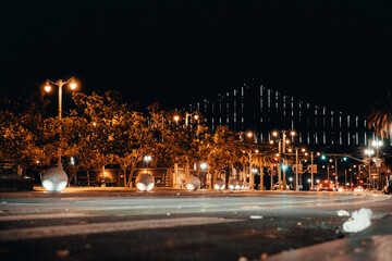 Fototapeta na wymiar Night Photography of Streets in San Francisco. Streetlamps in the foreground, Oakland Bay Bridge in the background. Water.