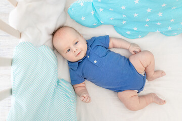 baby boy in a cot among pillows, concept of baby linen and textiles