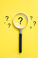 A yellow background with question marks and a magnifying glass