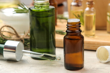 Natural rosemary essential oil in a glass bottle and a fresh sprig of rosemary on a light background. face and body skin care. spa.