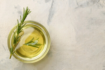 Natural rosemary essential oil in a glass bottle and a fresh sprig of rosemary on a light background. face and body skin care. spa.