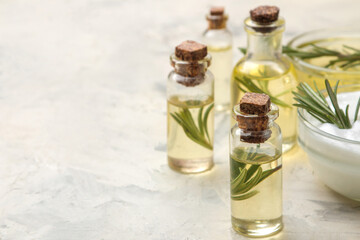 Natural rosemary essential oil in a glass bottle and a fresh sprig of rosemary on a light background. face and body skin care. spa.