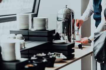 The waiter preparing coffee for hotel guests. Close up photo of service in modern hotels