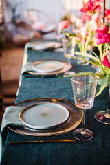 Family holidays in modern dining room. Stylish spring party. Wedding. Festive dinner table is served dishes, cutlery, decorated with flowers tulips and greenery, candle. Birthday celebration. Sunlight