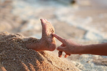 Pointing fingers, sandy feet on the sand.