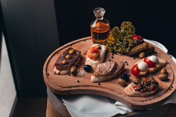 A wooden platter with a variety of food including meat, olives, olives, and olives.