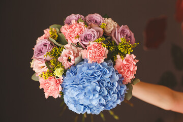 A woman holds a bouquet of flowers with a blue ball in the middle.