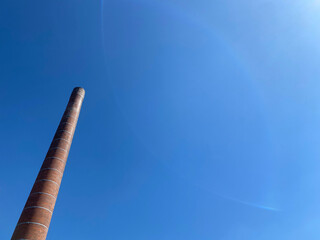 Red brick smokestack. Old chimney of a factory against blue sky.