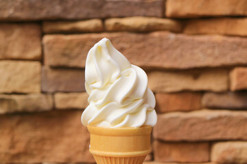 Delectable Vanilla Soft Serve Ice Cream Cone with Blurry Stone Blocked Wall in the Backdrop