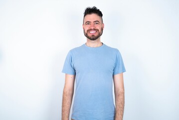 Obraz premium Young caucasian man wearing blue T-shirt over white background with nice beaming smile pleased expression. Positive emotions concept