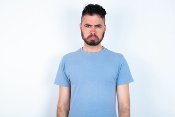 Obraz premium Young caucasian man wearing blue T-shirt over white background depressed and worry for distress, crying angry and afraid. Sad expression.