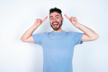 Fototapeta premium Cheerful Young caucasian man wearing blue T-shirt over white background demonstrating hairdo