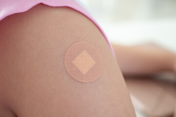 Vaccinated little asian girl with adhesive plaster after vaccine injection