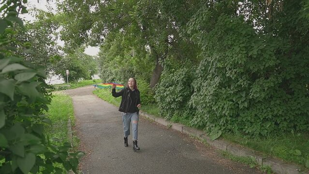 a woman with pink hair is flying a kite. slow motion video. a woman runs in the park with a kite in her hand along the path. High quality Full HD video recording