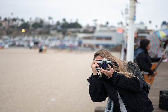 Portrait of a young girl taking photos with her vintage camera at the Santa Monica pier
