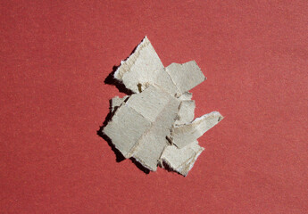 Pile of ripped paper pieces on an isolated red background. Top view, flat lay.