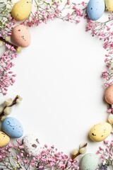 Shot from above of Easter composition with spring flowers and colorful quail eggs over white background. Springtime and Easter holiday concept with copy space. Top view