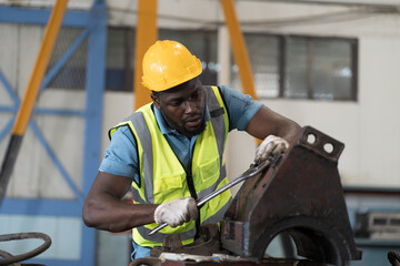 Male engineer worker working and inspecting parts quality of CNC machine in industry factory, wearing safety uniform, helmet and gloves. Male technician worker maintenance parts of machine