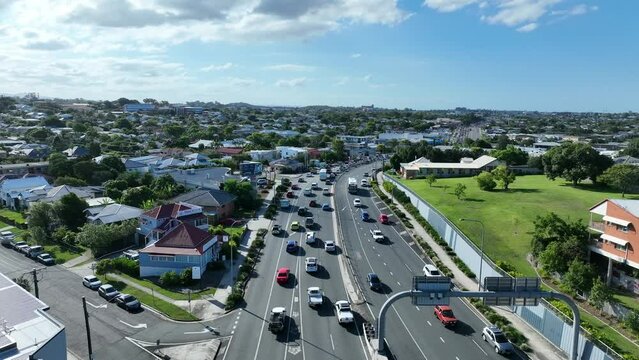 Drone shot of heavy traffic on Gympie Road, Kedron, Brisbane. Camera orbiting the standstill traffic. Shot in afternoon light with blue skies.
