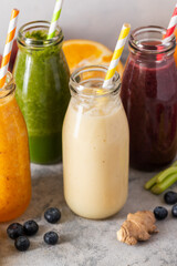 Bottles with fruit smoothies and colourful straws. Healthy detox drinks, bright background
