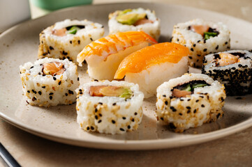 Sushi rolls closeup, with salmon, shrimp, avocado i n a round plate.