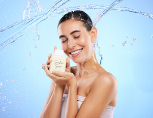 Happy woman, water splash and face with skincare moisturizer, product or cream against blue studio background. Calm female with smile holding lotion or creme for beauty cosmetics or facial treatment