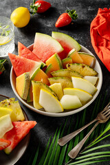 Fruits assortment platter antipasti, watermelon, pineapple, melon and strawberries. Dark background