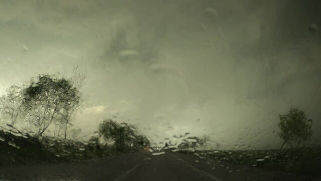 Driving along the road during a stormy rain, dashcam POV footage of rain-soaked windscreen glass and highway