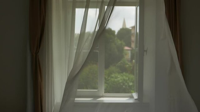 Window curtains moving in summer breeze through window at seaside apartment, slow motion