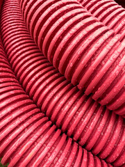 pile of plastic pipes wet from the rain, corrugated burgundy pipes, magenta