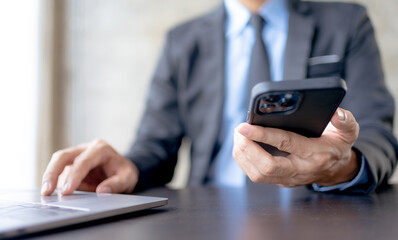 Businessman using smartphone to send text messages in the office.