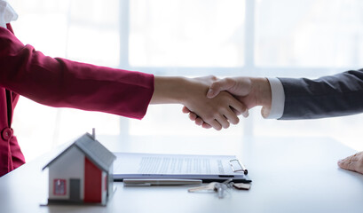 Real estate agent shaking hands with a client to sign a home purchase contract and congratulate the client.