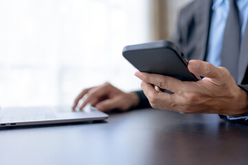 Businessman using smartphone to send text messages in the office.