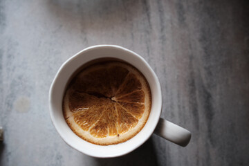 orange slice in herbal tea in white cup on gray background