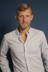 Blonde young man standing confident, portrait on studio background. Business, couch, office concept
