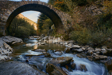 Viejo puente de piedra sobre arroyo en las montañas