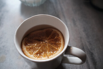 orange slice in herbal tea in white cup on gray background