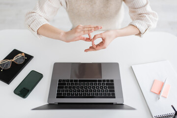 cropped view of teacher showing interpretation sign on body language near laptop and smartphone on...