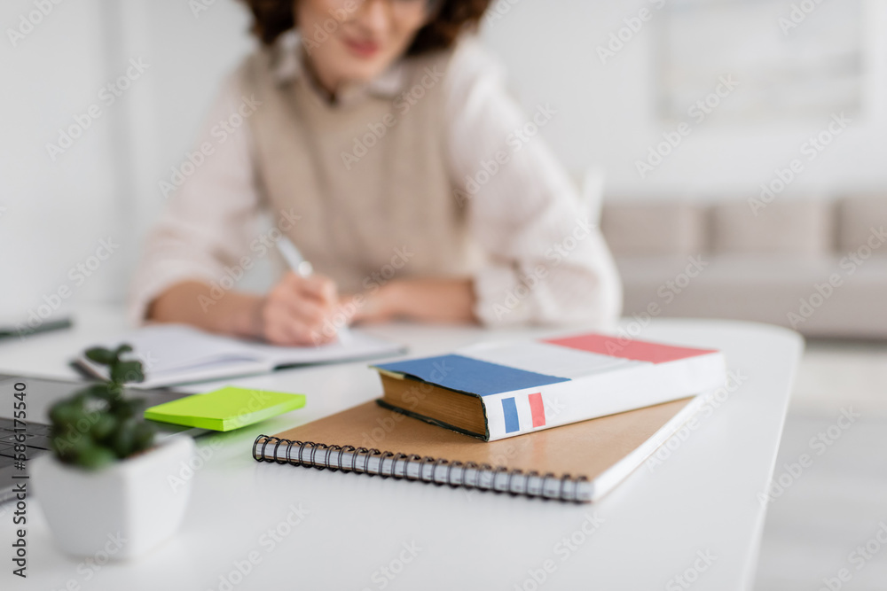 Wall mural dictionary book on notepad near student taking notes during lesson on blurred background.