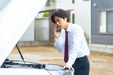 車が故障して電話連絡する男性