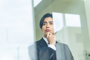窓から外を見る若いビジネスマン