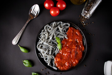 Black pasta with tomato sauce. On a black background. delicious