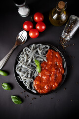 Black pasta with tomato sauce. On a black background. delicious