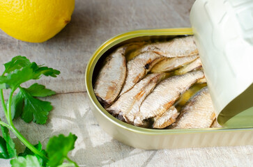 Canned fish with a sprig of parsley and lemon on a wooden table. Tinned fish concept. Rustic style. Horizontal orientation.