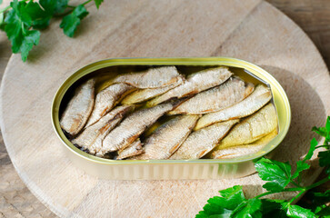 Canned fish with a sprigs of parsley on a wooden table. Tinned fish concept. Rustic style. Horizontal orientation.