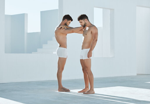 Connection, gay and men touching arms for LGBTQ, power and creative contemporary art. Love, artistic and homosexual male couple or friends standing in underwear by a white open outdoor space.
