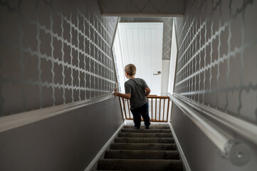Child going down the steep stairs at home with baby safety gate. Boy in motion, opening fence