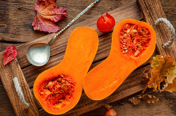 Overhead shot of halved orange pumpkin on rustic wooden tray. Harvesting and rural still life...